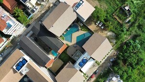 An aerial view of a residential area with multiple houses, a swimming pool, and a small garden area. - Duplex Vista Lagoa by La Playa (Ipojuca)