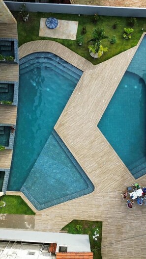 A modern pool area with multiple swimming pools and a wooden deck. - Duplex Vista Lagoa by La Playa (Ipojuca)