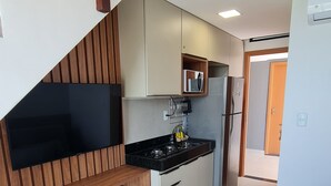A modern kitchen with a built-in stove, white cabinets, and a wooden bench. - Duplex Vista Lagoa by La Playa (Ipojuca)