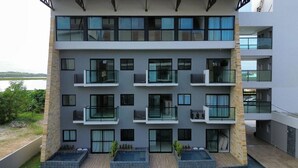A multi-story residential building with balconies, large windows, and a pool area. - Duplex Vista Lagoa by La Playa (Ipojuca)