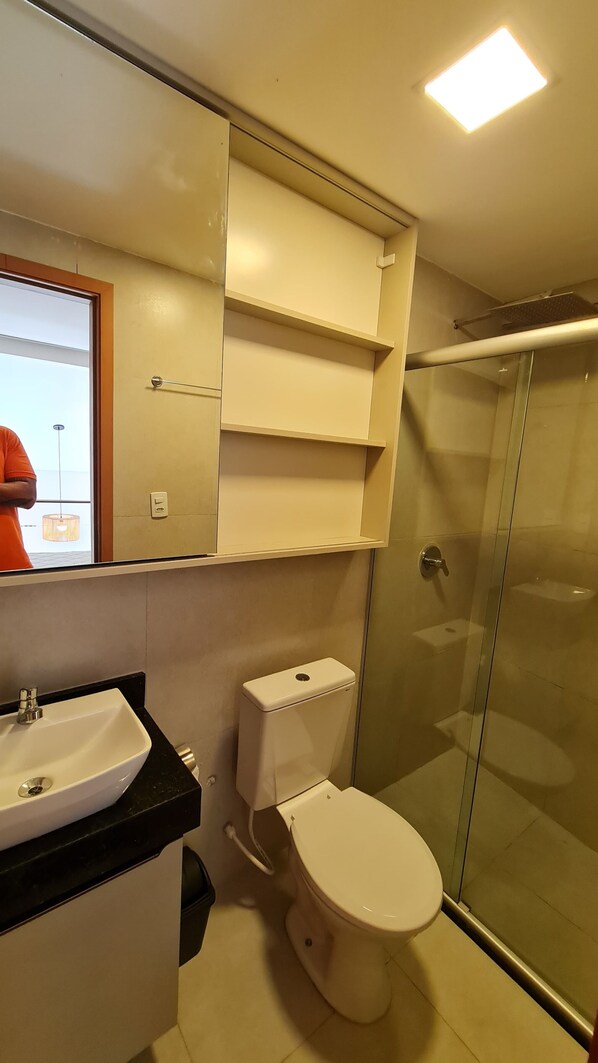 A bathroom with a toilet, sink, and glass shower enclosure. - Duplex Vista Lagoa by La Playa (Ipojuca)