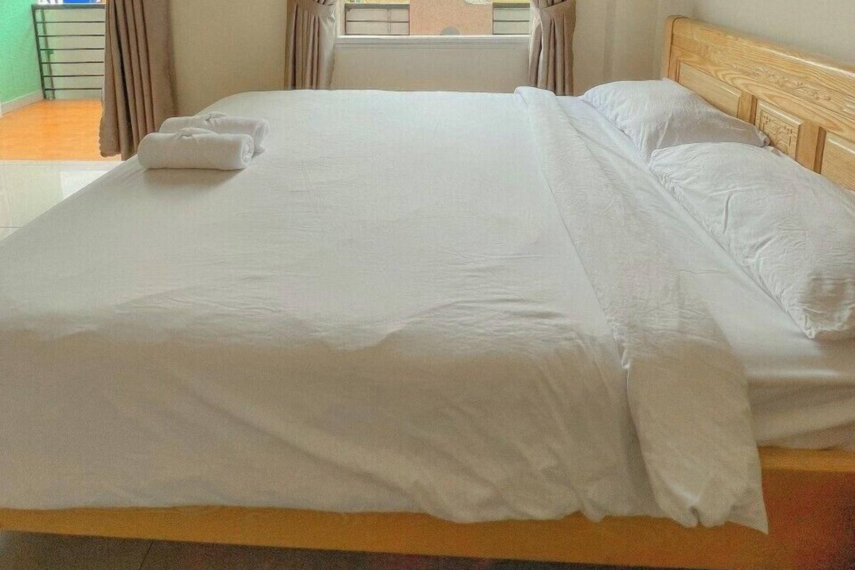 A hotel room with a large bed, curtains, and a view of buildings outside.