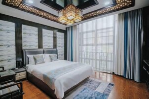 Un dormitorio con una cama grande, una mesita de noche, un aparador y una ventana con cortinas.