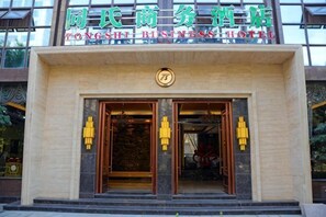 A hotel entrance with a sign in a foreign language, double doors, and a logo above the doors. - TS Business Hotel (Meishan)