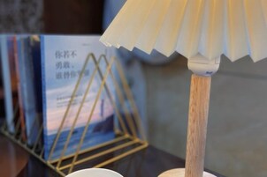 Una lámpara con base de madera y pantalla blanca sobre una mesa.