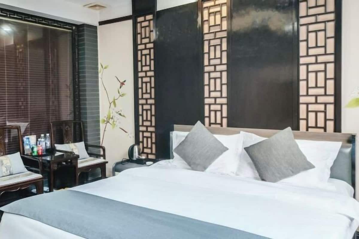 A hotel room with a bed, bedside table, lamp, and a decorative wall panel.