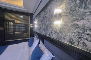 A bedroom with a bed, a wall with a nature-themed mural, and a window with blinds. - TS Business Hotel (Meishan)