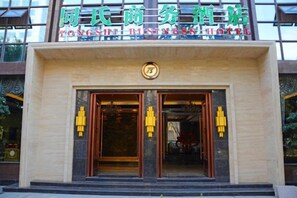 Ein Hotel Eingang mit einem Schild in einer Fremdsprache, einer Doppeltür und einem kleinen runden Wappen über den Türen.