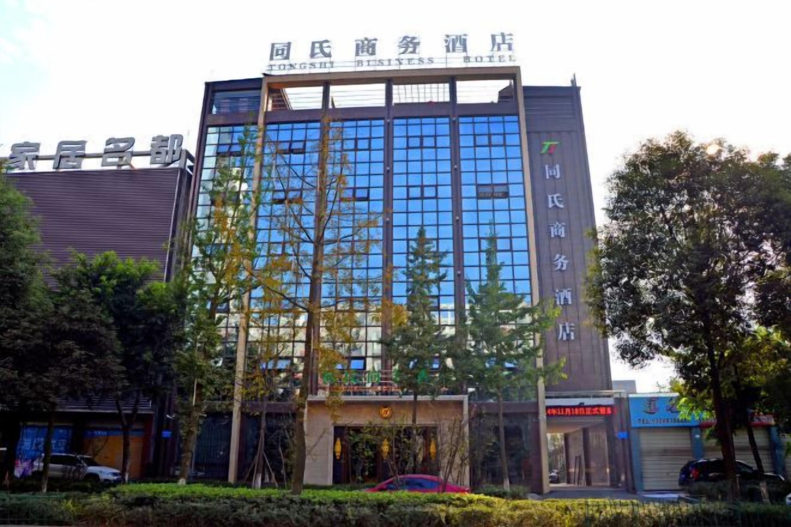 A modern hotel building with a glass facade, a prominent entrance, and signage indicating it is a business hotel.
