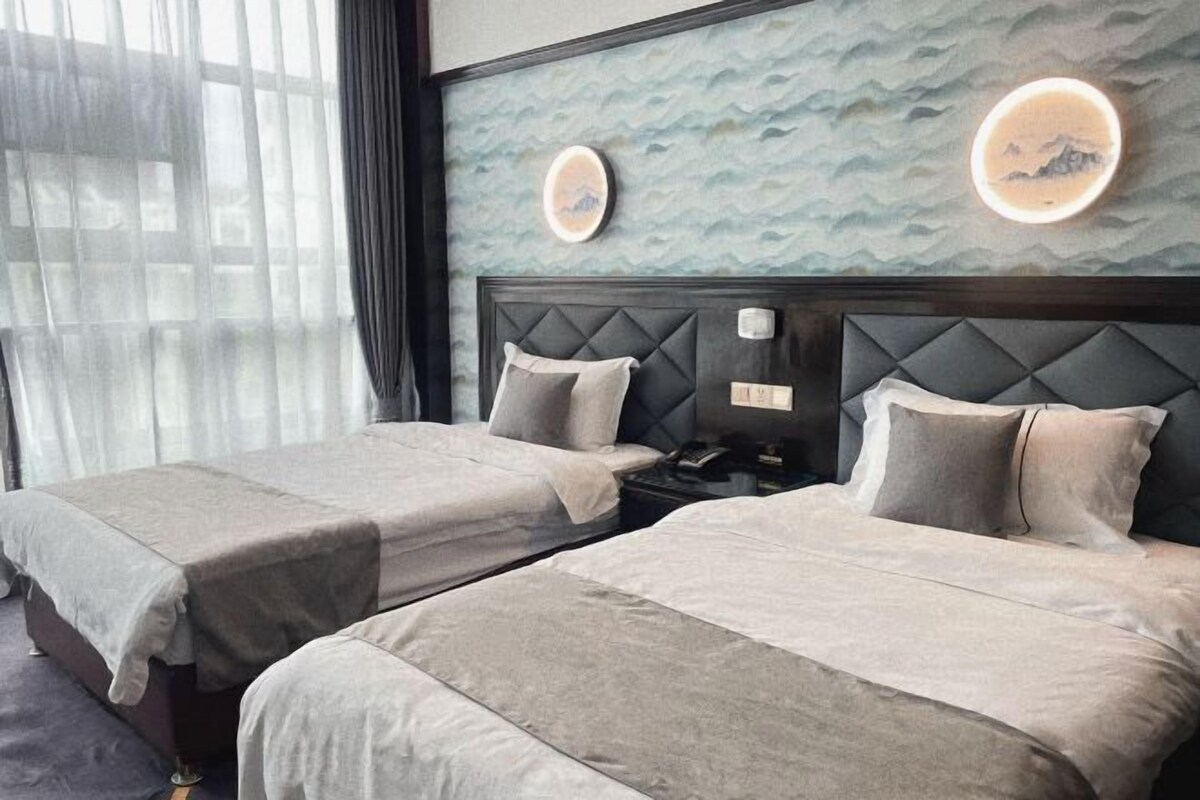 A hotel room with two beds, a nightstand, and a wall with decorative elements.