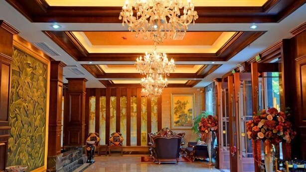 Eine Lobby mit einem Chandelier, Holzvertäfelung und einer großen Blumenvase.