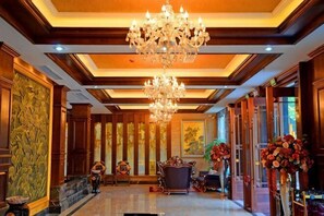 A lobby with a chandelier, wooden paneling, and a large vase of flowers. - TS Business Hotel (Meishan)