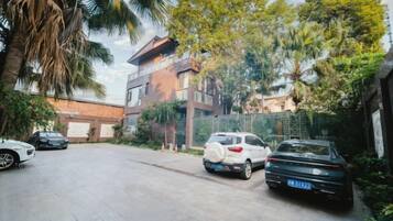 Un estacionamiento con coches, un edificio de varios pisos y vegetación circundante.