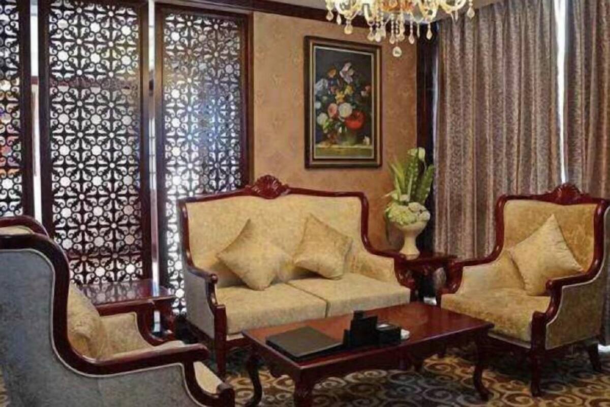 A traditional room with a sofa, armchairs, a coffee table, a chandelier, and a floral painting on the wall.