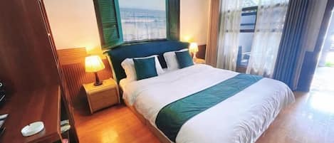 A hotel room with a bed, bedside tables, a window with a view, and curtains.