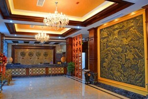Un vestíbulo con mostrador de recepción, candelabros y un gran mural decorativo.