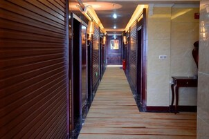 A corridor with closed doors, a wooden floor, and a tiled wall.