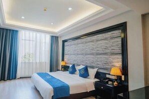 A modern hotel room with a large bed, two bedside tables, a nightstand, and a wall-mounted TV. - TS Business Hotel (Meishan)
