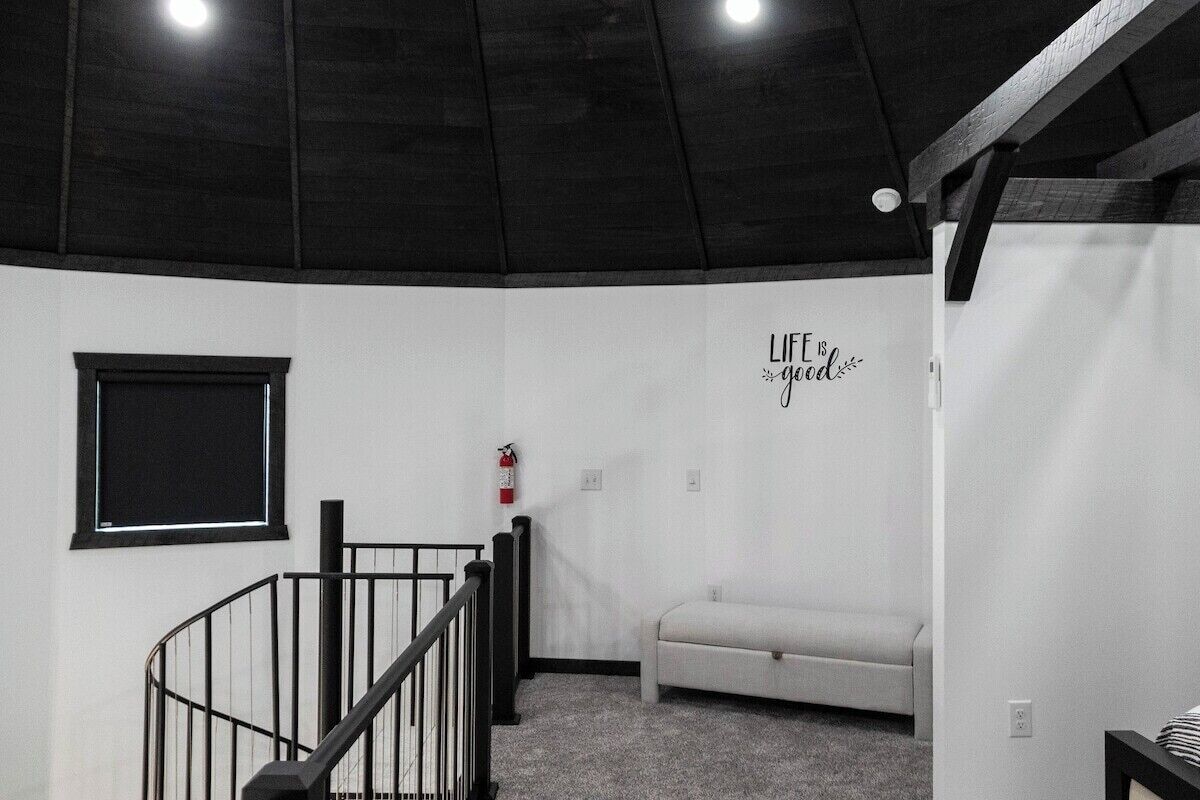 Une pièce avec un escalier, un extincteur, un canapé et un mur sur lequel est écrit : « La VIE est belle ».