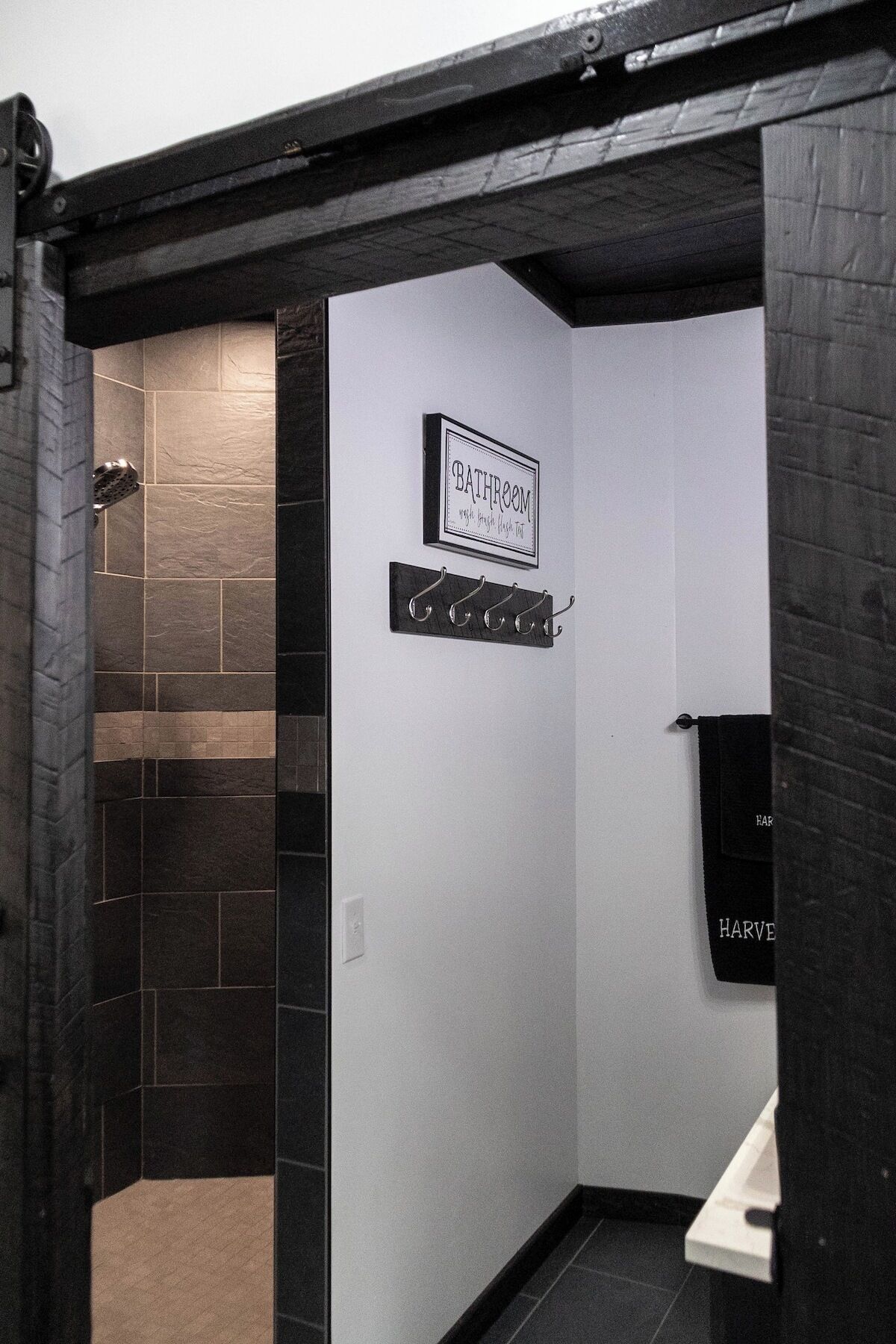 A bathroom with a shower, a towel rack, and a sign that reads 'BATHROOM.'