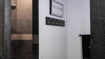 A bathroom with a shower, a towel rack, and a sign that reads 'BATHROOM.'