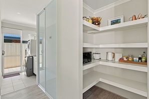 A modern kitchen with built-in appliances, a microwave, a kettle, and a coffee maker on the countertop.