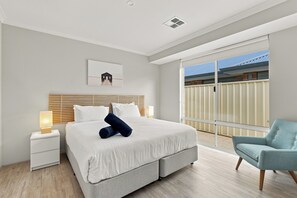 A modern bedroom with a large bed, a bedside table, a chair, and a view of the outside. - Modern Getaway in Dunsborough (Dunsborough)