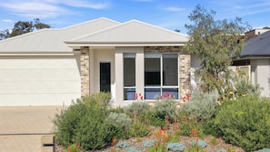 A residential building with a garage, a covered porch, and a landscaped garden with various plants and flowers. - Modern Getaway in Dunsborough (Dunsborough)