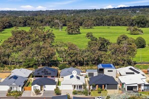 A residential area with modern houses featuring solar panels, surrounded by green fields and trees. - Modern Getaway in Dunsborough (Dunsborough)