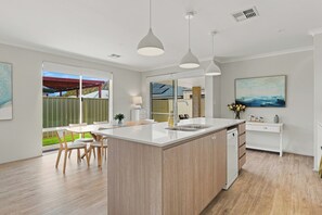 A modern kitchen with a central island, pendant lighting, and a view to the outside. - Modern Getaway in Dunsborough (Dunsborough)