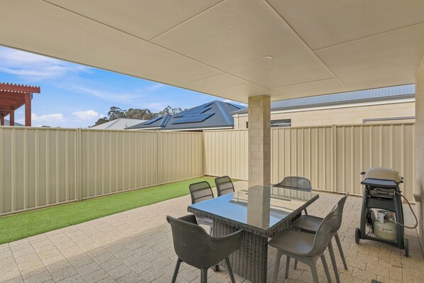An outdoor patio with a table and chairs, a grill, and a gas cylinder. - Modern Getaway in Dunsborough (Dunsborough)