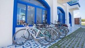 Un bâtiment moderne à l’architecture bleue et blanche, doté de grandes fenêtres et d’un hall d’entrée carrelé, avec des vélos garés à l’extérieur.