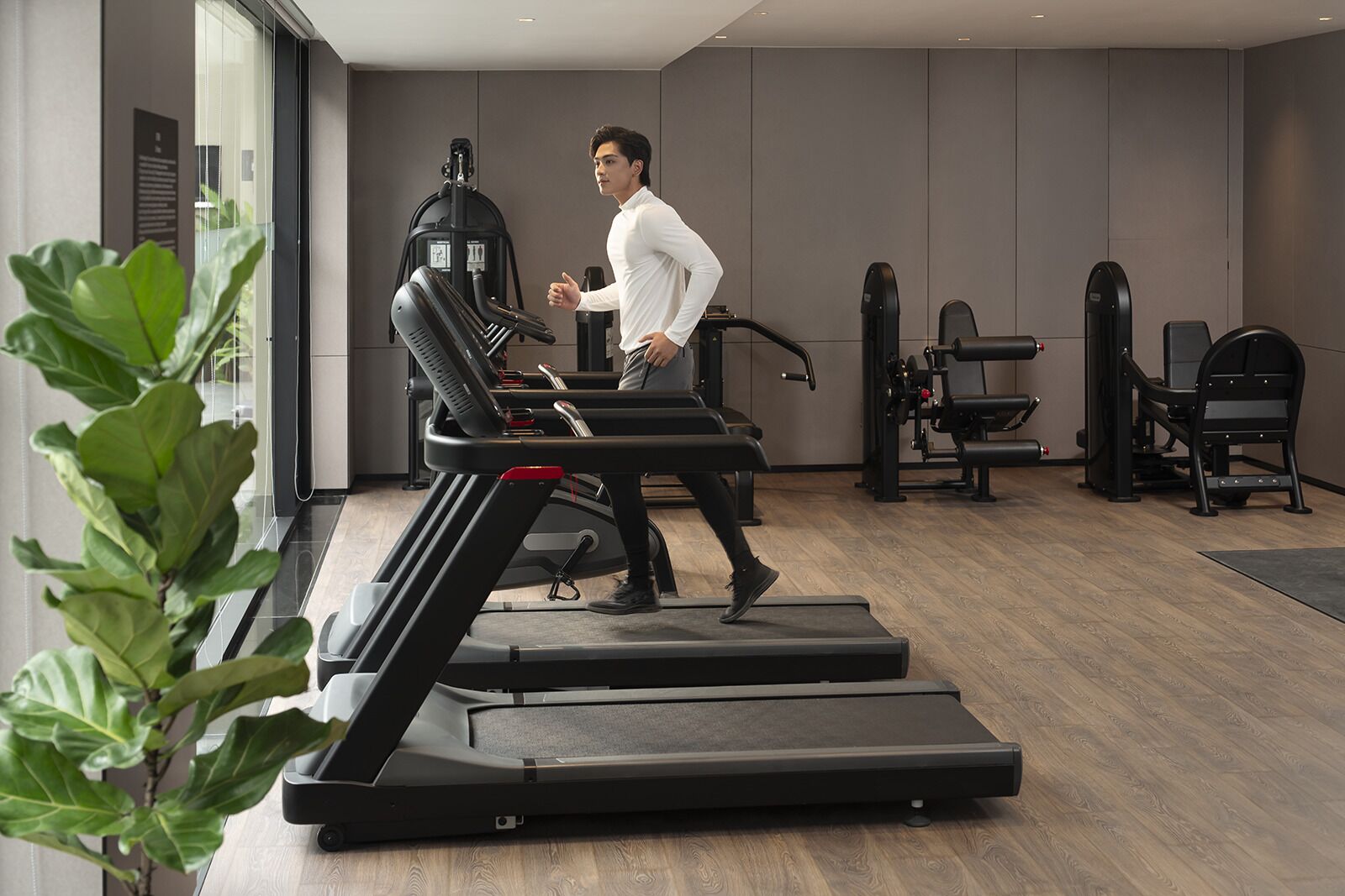 Un gimnasio moderno con cintas de correr, máquinas de pesas y un espejo grande.