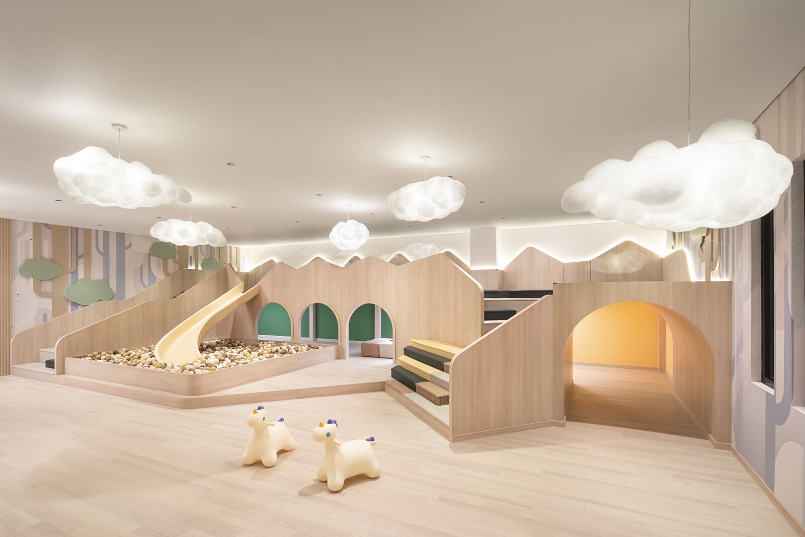 A children's play area with a slide, climbing stairs, and cloud-shaped lighting fixtures.