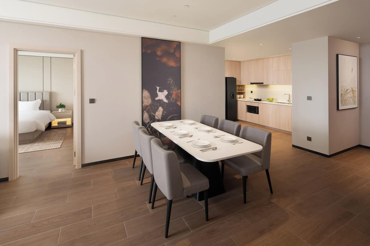 A modern dining area with a rectangular table set for six, surrounded by six grey chairs.