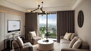 Ein modernes Hotelzimmer mit großem Fenster, Flachbildfernseher, rundem Couchtisch und zwei Sofas.