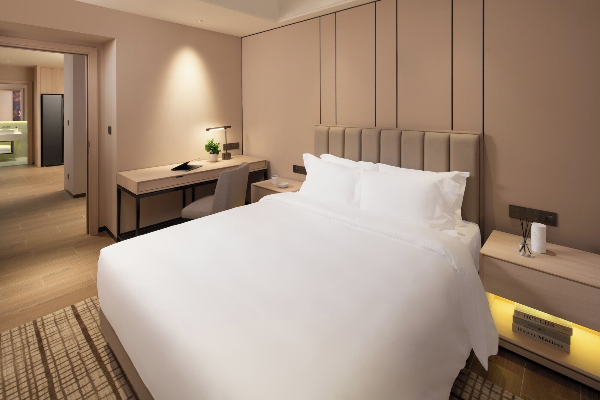 A modern hotel room with a large bed, a desk, and a nightstand.