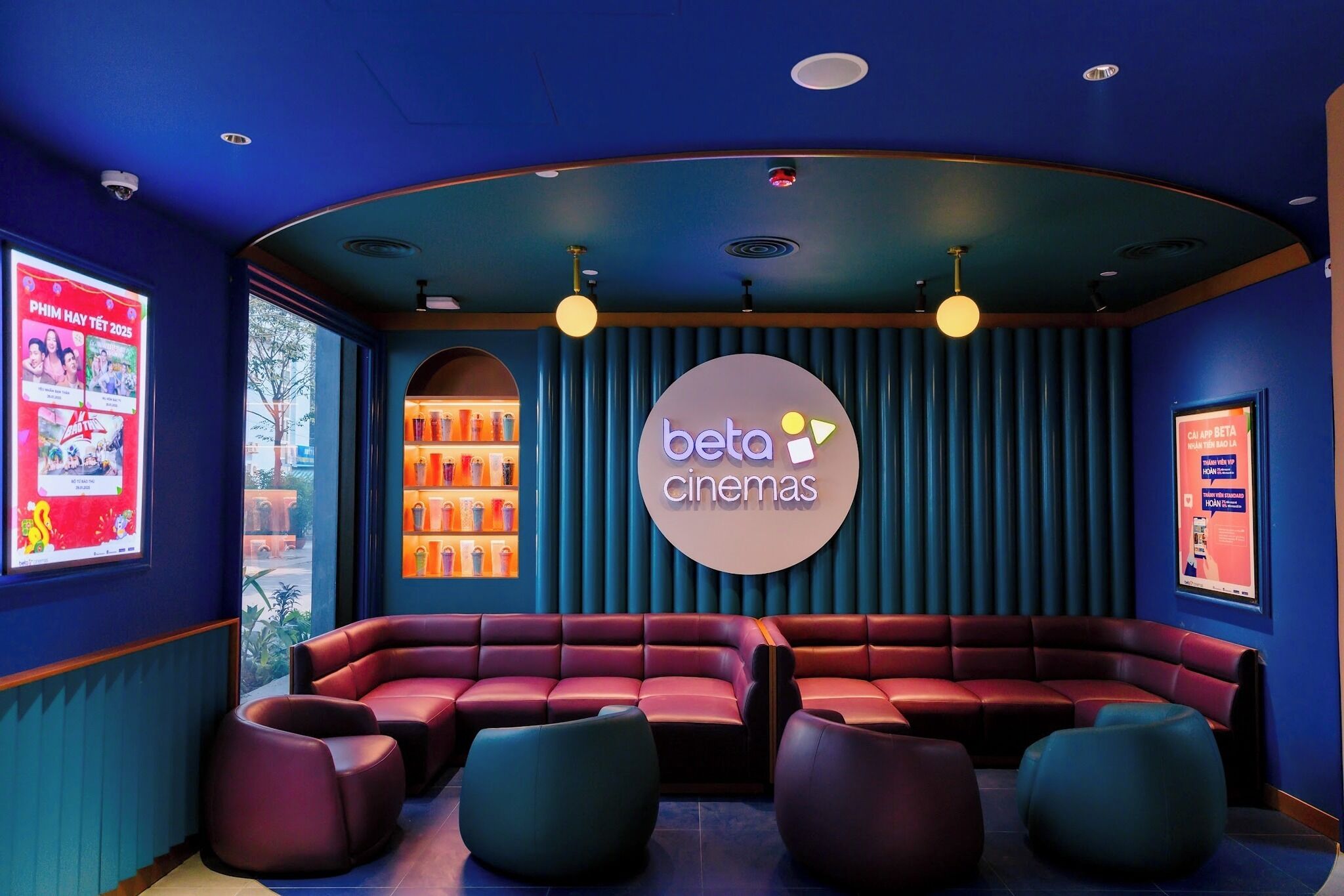 Een bioscoop met een gebogen plafond, rode zitplaatsen en een 'beta cinemas' bord.
