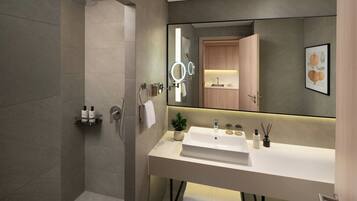A modern bathroom with a large mirror, a shower, and a white sink with a countertop.