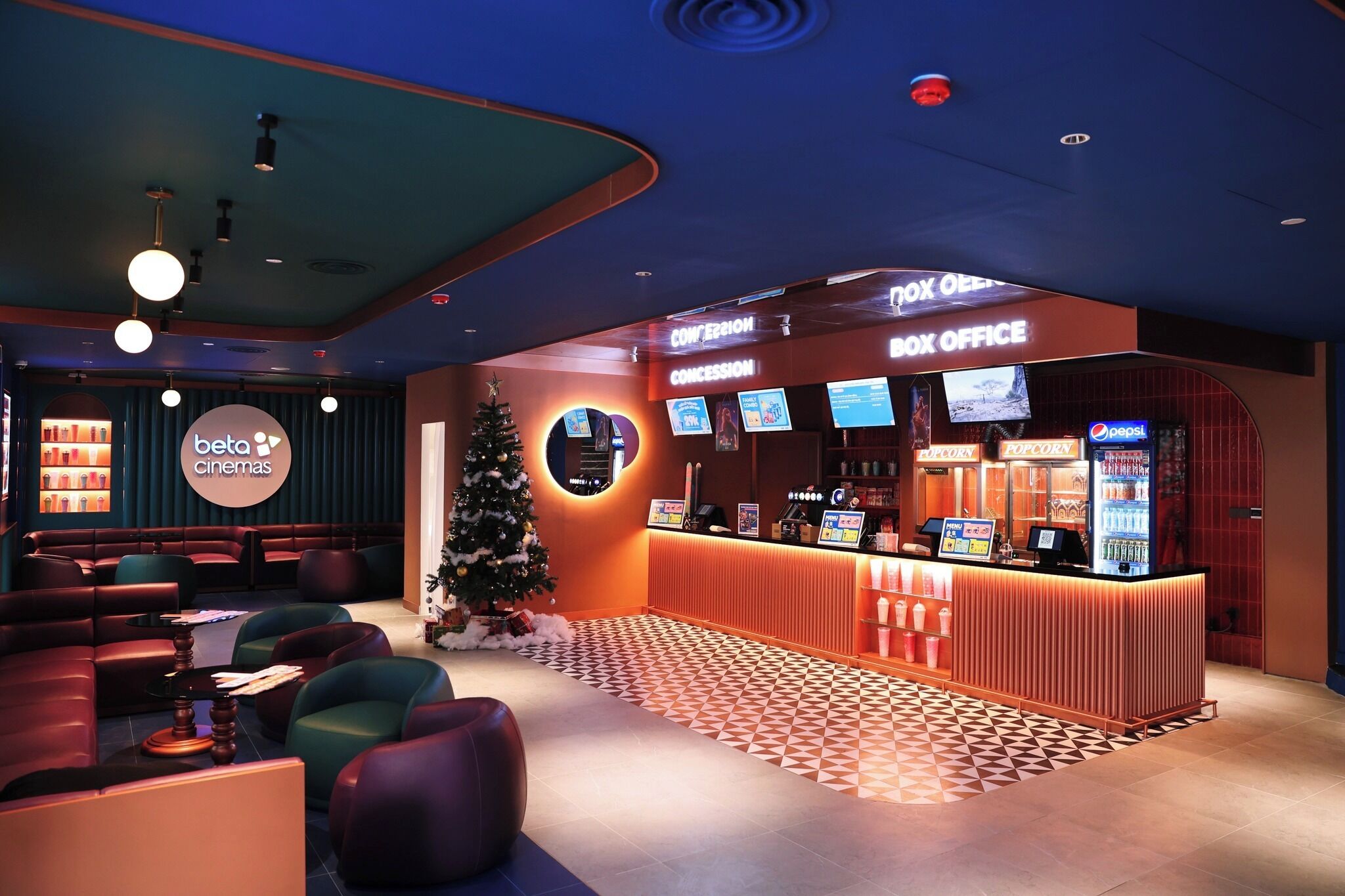 A cinema lobby with seating, a concession stand, and a Christmas tree.