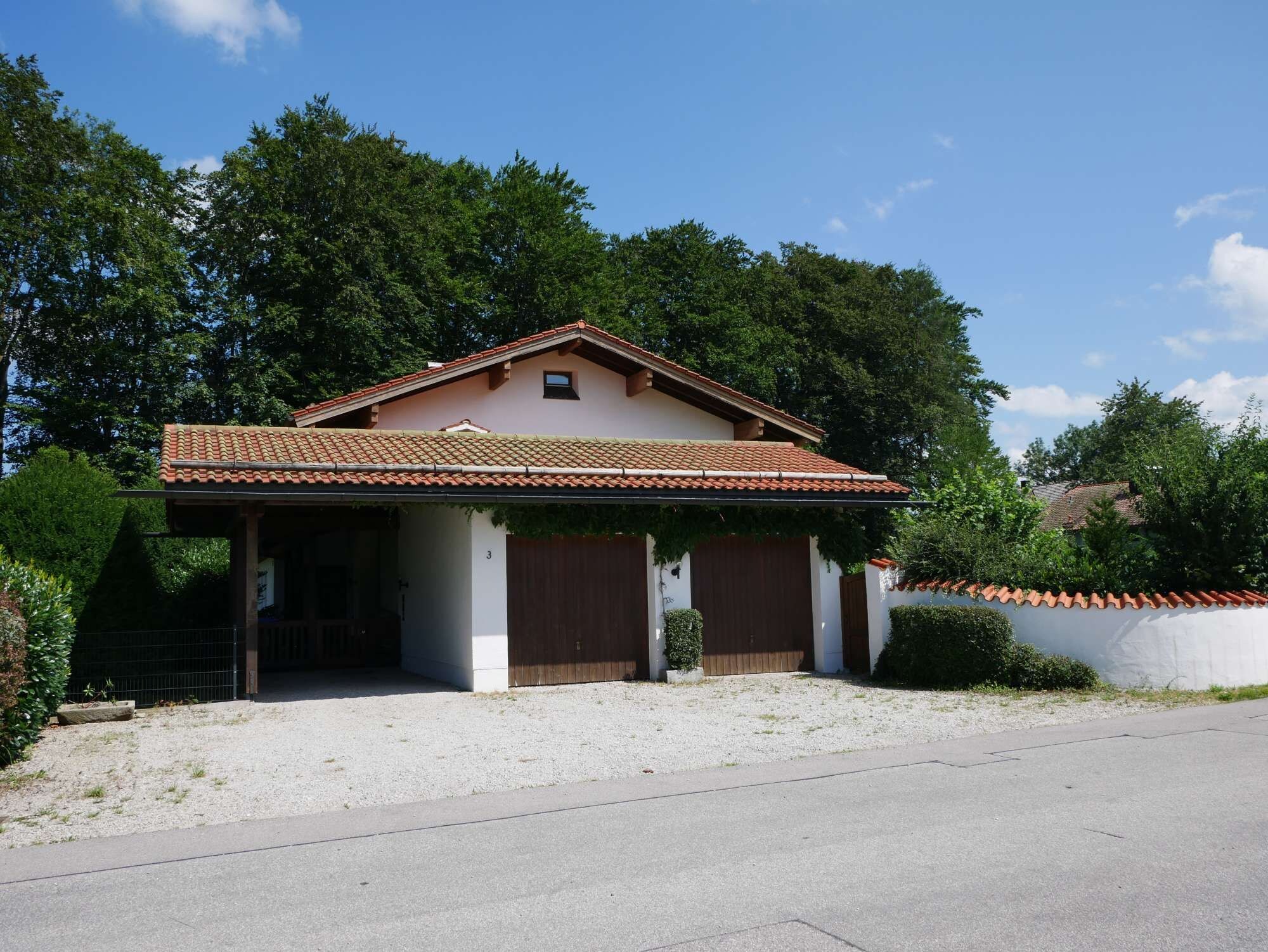 Ein eingeschossiges Haus mit einem Ziegeldach, einer Veranda und einer Zuwegung mit Kies.