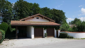 Ein eingeschossiges Haus mit einem Ziegeldach, einer Veranda und einer Zuwegung mit Kies.