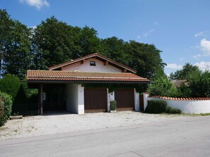 Ein eingeschossiges Haus mit einem Ziegeldach, einer Veranda und einer Zuwegung mit Kies.