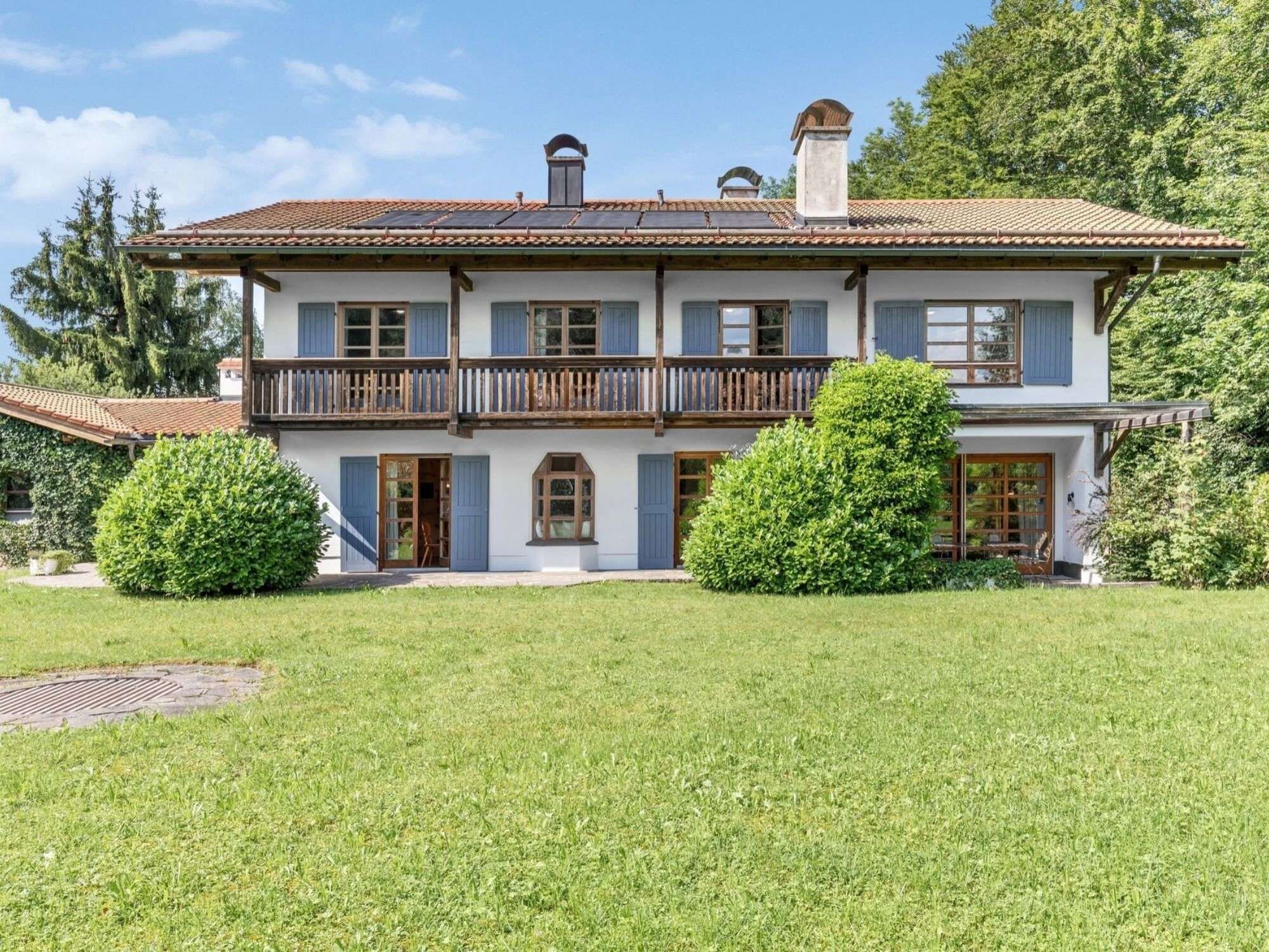 Ein zweigeschossiges Haus mit Balkon, Eingangstür und kleinem Garten.