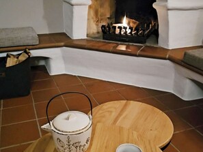 A cozy room with a fireplace, a white kettle on a tray, and a wooden table.
