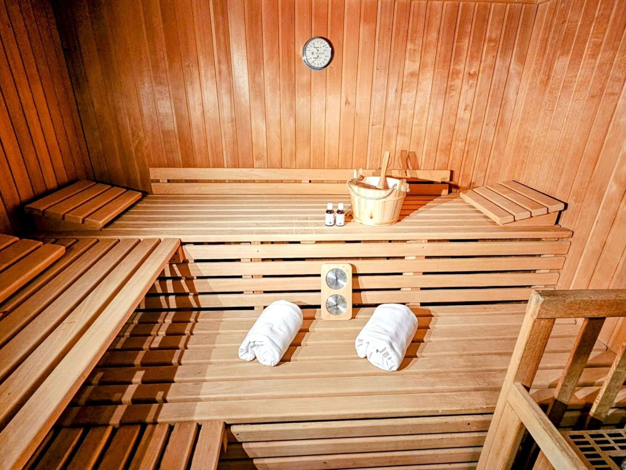 Una sauna con bancos de madera, un balde y toallas.