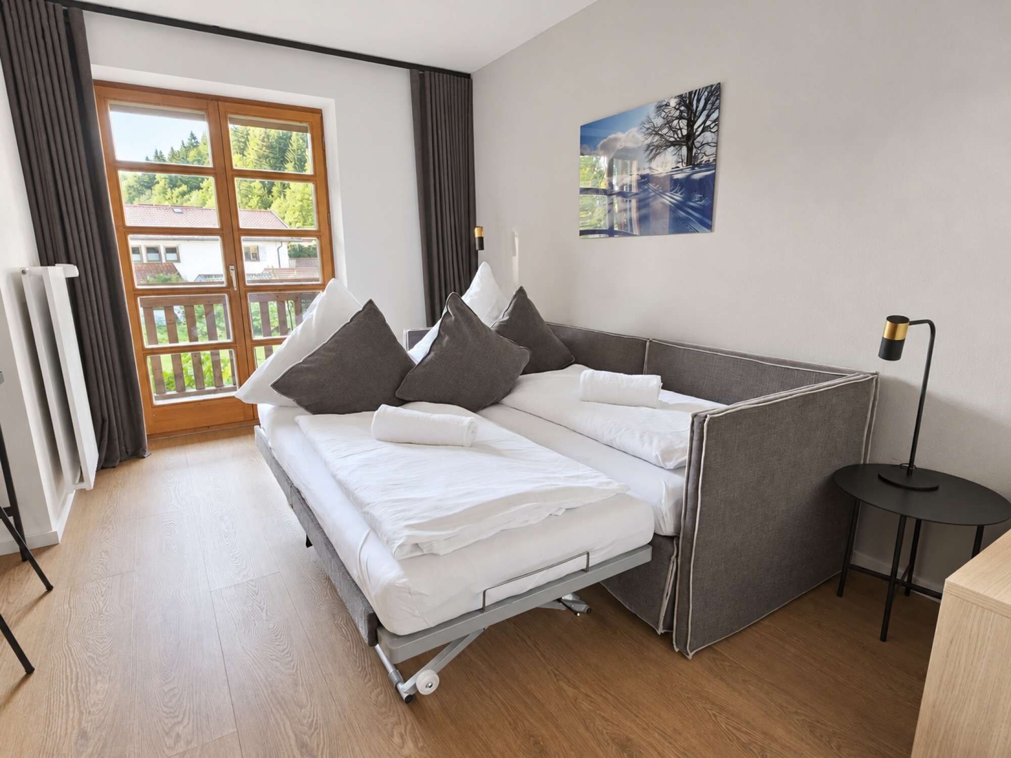 Ein modernes Schlafzimmer mit einem Bett, einem kleinen Tisch und einem Bild an der Wand.
