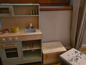 Une cuisine miniature pour enfants, avec un évier, un four et divers ustensiles.