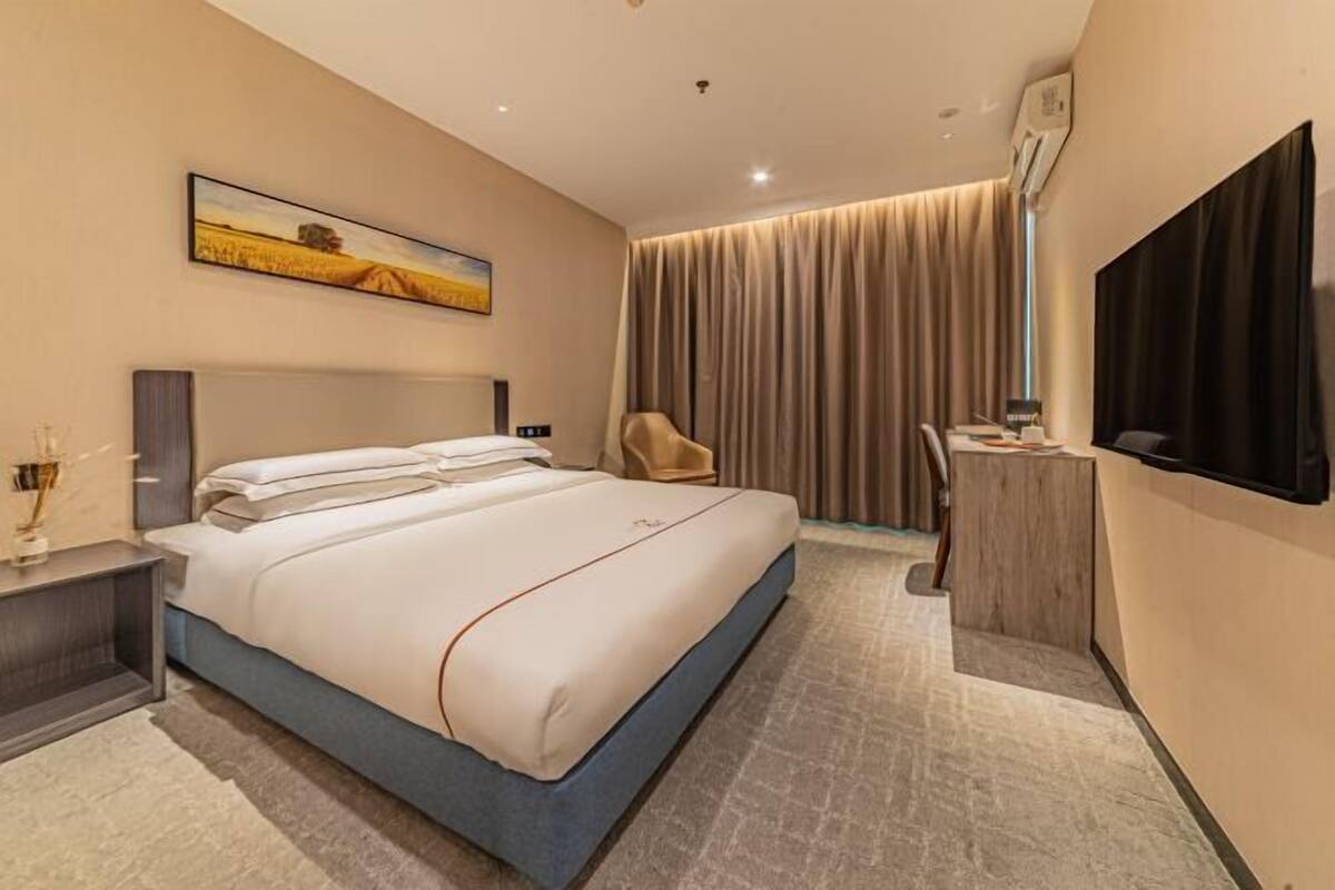Una habitación de hotel moderna con una cama grande, un escritorio, una silla y un televisor.