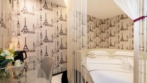 A room with a glass table, a chair, a bed with white linens, and a wall with Eiffel Tower wallpaper. - Hotel Z (Shenzhen Futian Nonglin Subway Station) (Shenzhen)